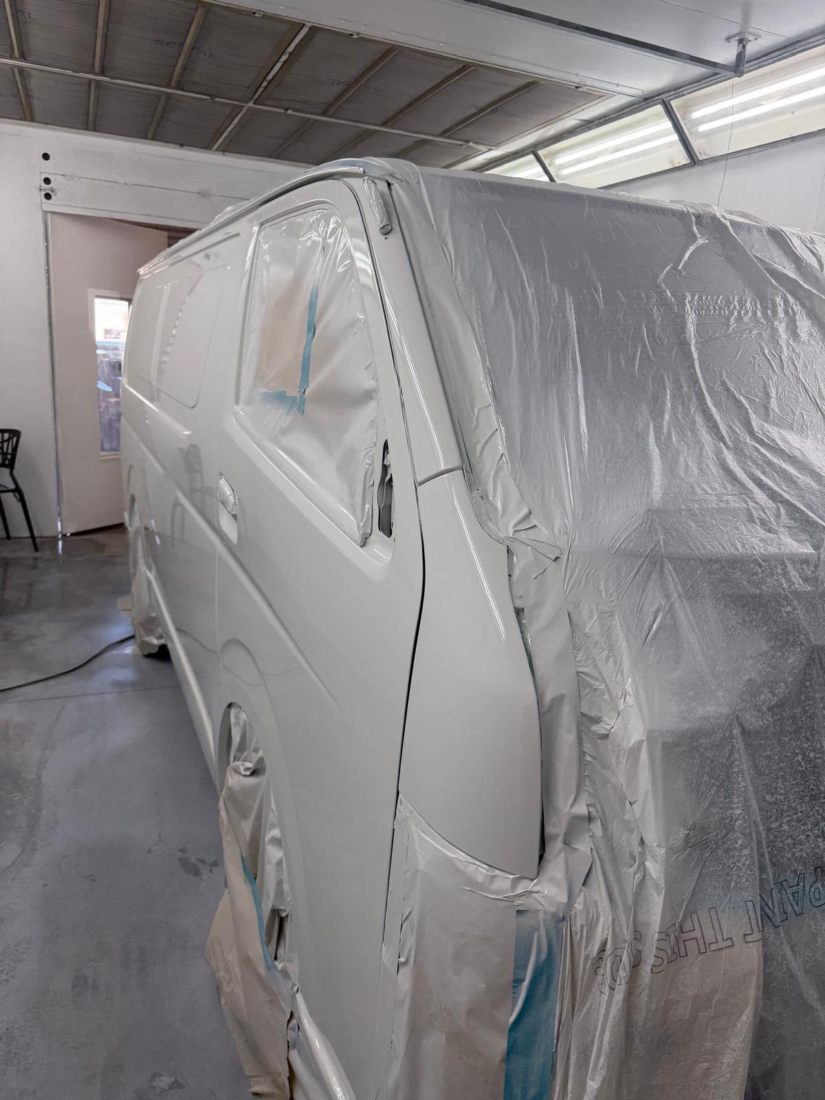 White commercial van fully masked and prepped inside spray booth